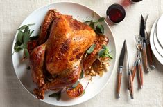 a whole chicken sitting on top of a white plate next to silverware and utensils