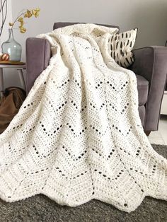 a white crocheted blanket sitting on top of a couch next to a chair