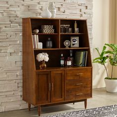 a wooden bookcase sitting next to a brick wall in front of a potted plant