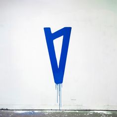 a large blue v on the side of a white wall with paint dripping from it