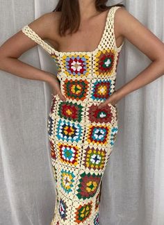 a woman in a crocheted dress poses with her hands on her hips