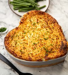 a heart shaped casserole with green beans on the side