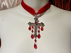 "Red velvet choker with large ornate gothic/medieval style cross pendant. the cross has a red glass \"rhinestone\" in its center, plus drippy red beads hanging from it. the choker adjusts between 13.5 to 16.5\",  so will fit necks up to about 15.5\" around  (should be a little loose, so that the cross will lay nicely on your chest). cross, with bead drops, is about 2\" wide, 4.5\" tall." Adjustable Red Gothic Jewelry, Gothic Cross Pendant Jewelry For Halloween, Adjustable Gothic Cross Pendant Jewelry, Red Adjustable Cross Necklace, Adjustable Red Cross Necklace, Red Gothic Cross Necklace, Ornate Cross, Ribbon Choker Necklace, Gothic Medieval