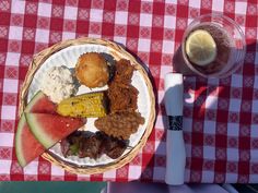 a plate of food on a picnic table with a glass of watermelon and knife