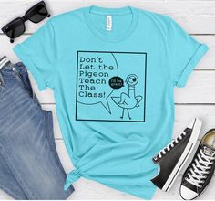 Inject some humor into your classroom with our hilarious "Don't Let the Pigeon Teach The Class!" T-Shirt! Perfect for teachers with a sense of wit, this shirt is bound to bring smiles and laughter to colleagues and students alike. Whether you wear it to school, teacher gatherings, or casual outings, it's sure to become a favorite conversation starter. Add a touch of fun to your wardrobe or surprise your favorite teacher with a gift that's as entertaining as it is stylish! PRODUCT FEATURES 👚 Sol Funny Tshirts For Teacher Assistants, Fun Tshirts Sayings For Work, Staff Tshirts Funny, Office Staff Shirts For Elementary, Teacher Team Shirts Comfy, Cute Teacher Shirts Comfy, Tee Shirts Staff Meeting Funny, Cute Teacher Vinyl Shirts, Womens Teacher Tshirt