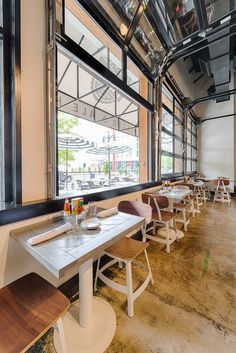 an empty restaurant with tables and chairs in front of large windows that look out onto the street