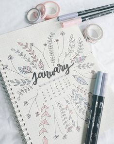 a notebook with the word january written in cursive writing on it next to two markers