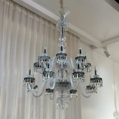 a crystal chandelier hanging from the ceiling in a room with sheer drapes