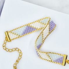 two bracelets on a white surface with gold chains and beaded beads, one in the shape of a rectangle