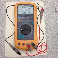 a multimeter and some electrical wires on a white board with a red cord attached to it