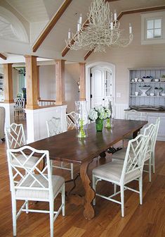 a dining room table with white chairs and a chandelier hanging from the ceiling