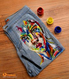 a pair of jeans with a painting on it and some paintbrushes next to it