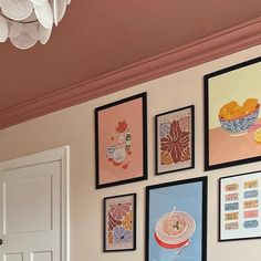 several framed pictures hang on the wall next to a white door with a chandelier