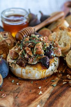 an assortment of breads, figs and honey on a cutting board with other food items