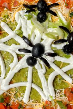 a pizza with black olives, lettuce and cheese on it's crust