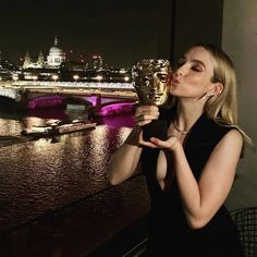 a woman holding an award in front of a cityscape and river at night