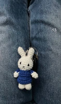 a crocheted bunny keychain hanging from the lap of someone's jeans