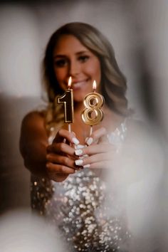 a woman holding a birthday cake with candles in her hand and the number eight on it