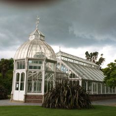 a large white glass house sitting in the middle of a lush green field under a cloudy sky