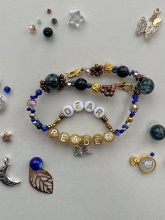 several bracelets with beads and charms on a white surface next to other jewelry items