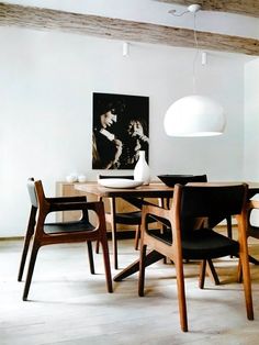 a dining room table and chairs in front of a painting on the wall above it