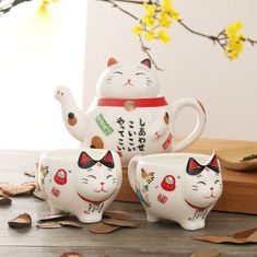 three ceramic cups with cats painted on them, one has a teapot in the shape of a cat