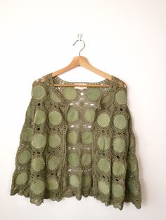 a green crochet top hanging on a wooden hanger