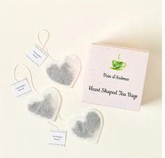 three heart shaped tea bags with tags attached to them on a white surface next to each other