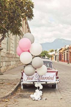 a truck with balloons attached to it parked in front of a building