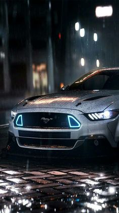 a silver mustang parked in the rain at night