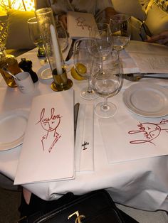 the table is set with wine glasses, plates and menus for two people to eat