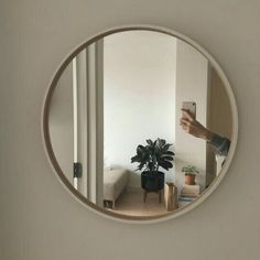 a person taking a selfie in a mirror with a houseplant on the table