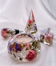 a candle and some glass vases on a white sheet with flowers in the center