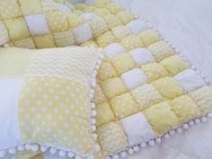 two yellow and white pillows sitting on top of a bed covered in polka dot fabric