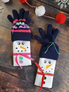 two snowmen made out of toilet paper on top of a wooden table