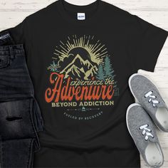 This Recovery T-Shirt encourages sobriety with a design featuring mountains and other outdoor elements, inspiring you to experience the adventure beyond addiction. Fueled by recovery, this T-Shirt is for anyone who wants to celebrate their journey of sobriety. 100% cotton (99/1 cotton/poly (Ash) & 90/10 cotton/poly (Sport Grey), 50/50 cotton/poly (Dark Heather) Heavyweight classic unisex tee Taped neck and shoulders; Tearaway label Made with sustainably & fairly grown USA cotton Print Method: DI Black Graphic Print T-shirt For Adventure, Black Graphic Tee For Camping, Black Graphic Print T-shirt For Camping, Black Graphic Print T-shirt For Outdoor, Black T-shirt With Screen Print For Adventure, Black T-shirt For Hiking With Letter Print, Black Screen Print T-shirt For Adventure, Black Letter Print T-shirt For Hiking, Black Hiking T-shirt With Letter Print