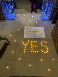 a sign that is on the ground with lights around it and people standing in the background