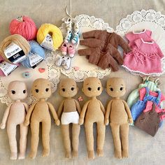 several knitted dolls are laid out on a table with crochet doily