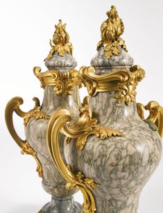 two ornate vases with gold trimming and marble designs on the sides, sitting next to each other