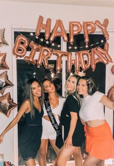 four women posing for a photo in front of a happy birthday sign