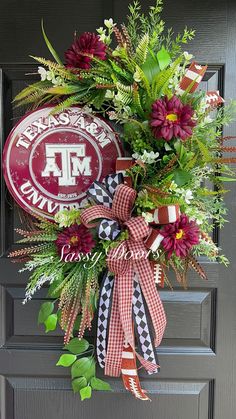 a wreath on the front door with flowers and a football hanging from it's side