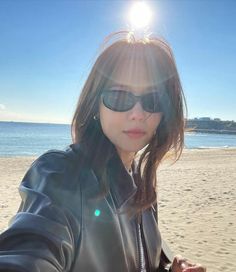 a woman in sunglasses taking a selfie on the beach