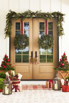 two christmas wreaths are on the front door and one is decorated with greenery