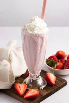 a drink with whipped cream and strawberries on a cutting board