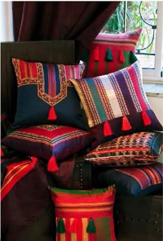 a bed with colorful pillows on top of it and a window in the back ground