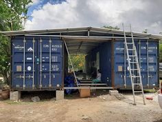 two men are working on the side of a blue shipping container that is under construction