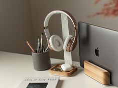 an apple computer sitting on top of a desk next to a book and headphones