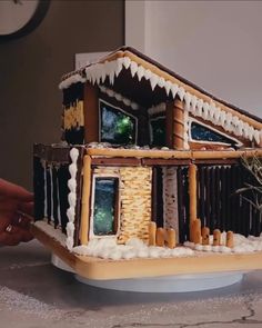 someone is decorating a gingerbread house with icing on the roof and windows