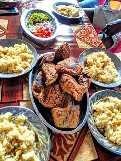 a table topped with plates of food and bowls filled with different types of meats