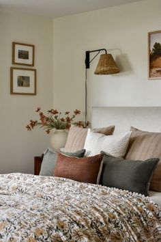 a bed with pillows and blankets on top of it next to a wall mounted lamp